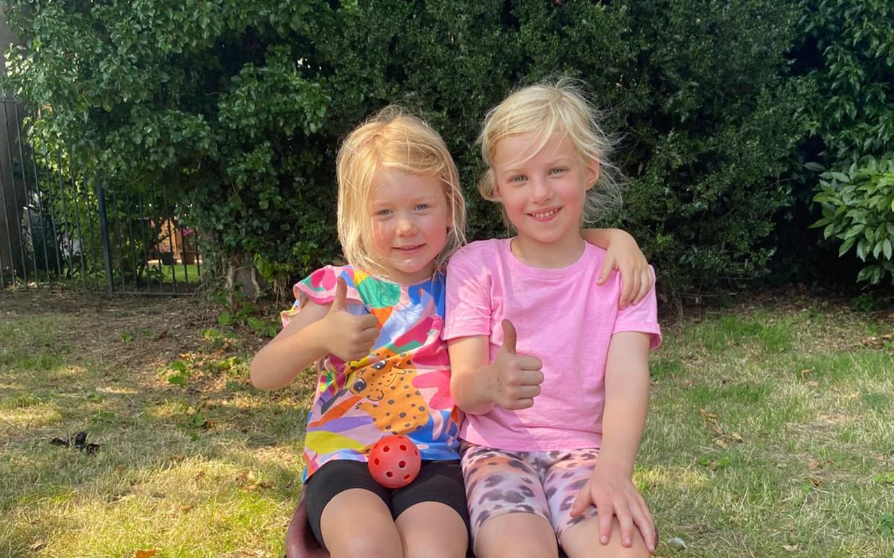 Two girls smiling and giving a thumbs up