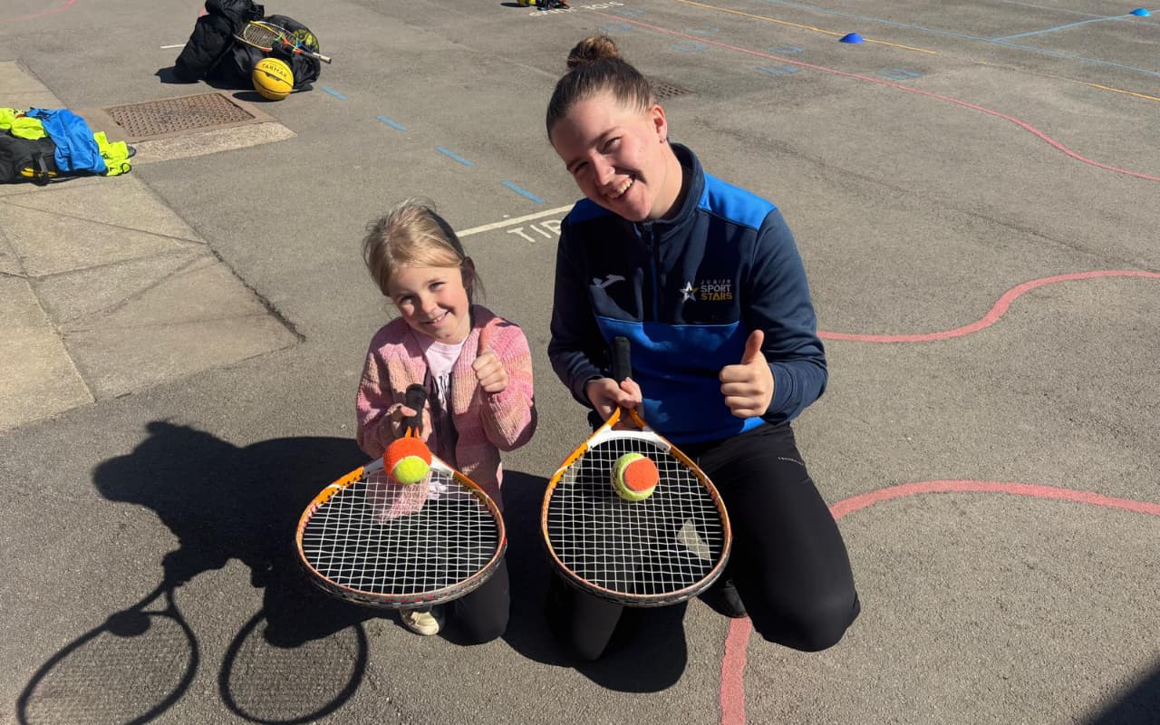 child and coach with tennis equipment
